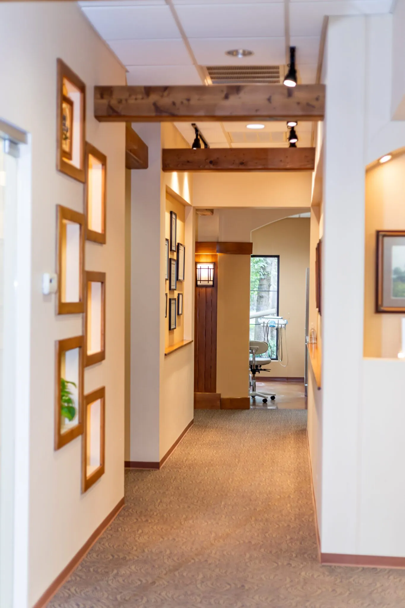 A sunlit wood-trimmed hallway leading to a treatment room at Oak Hills Dentistry