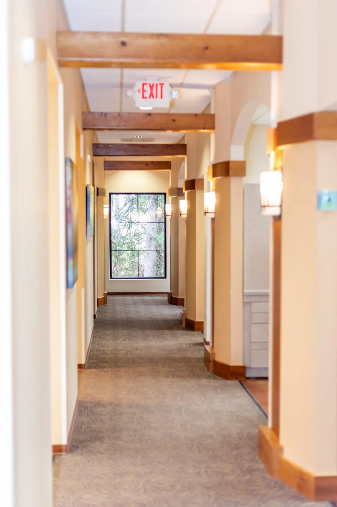A warm, softly lit corridor between treatment rooms at Oak Hills Dentistry