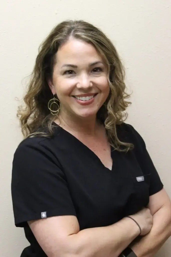 Arlene, registered dental hygienist at Oak Hills Dentistry, smiling with her arms folded in black scrubs