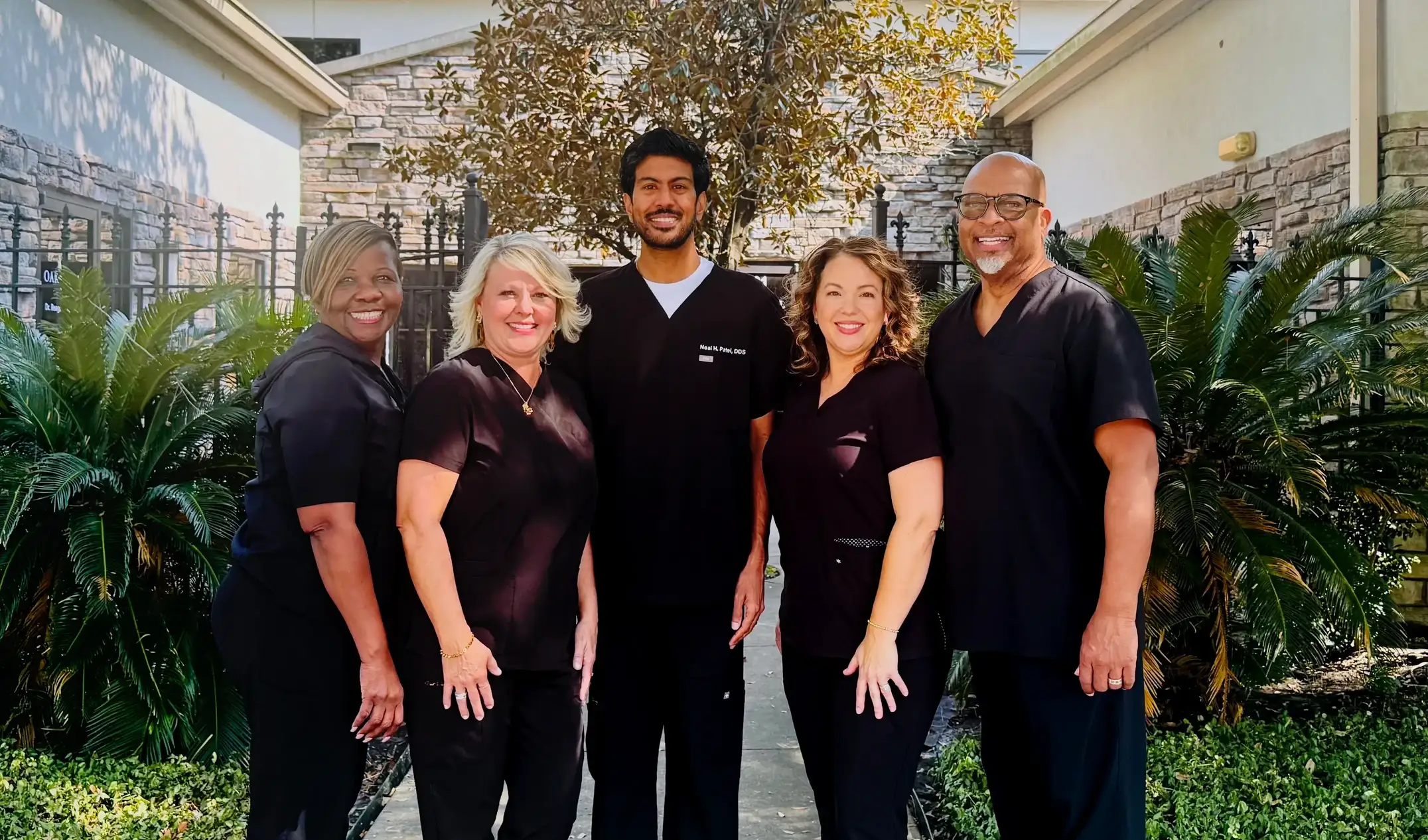 The Oak Hills Dentistry team in scrubs outside the practice on Louetta Road, with Dr. Neal H. Patel in the centre