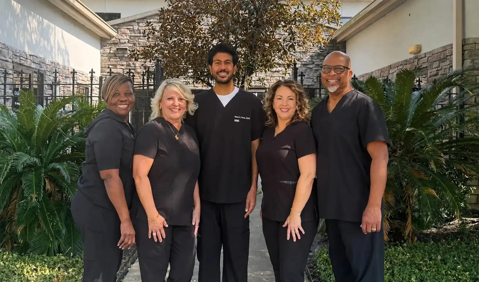 The Oak Hills Dentistry team in scrubs outside the practice on Louetta Road, with Dr. Neal H. Patel in the centre