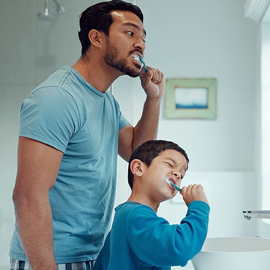 father and son brush teeth together