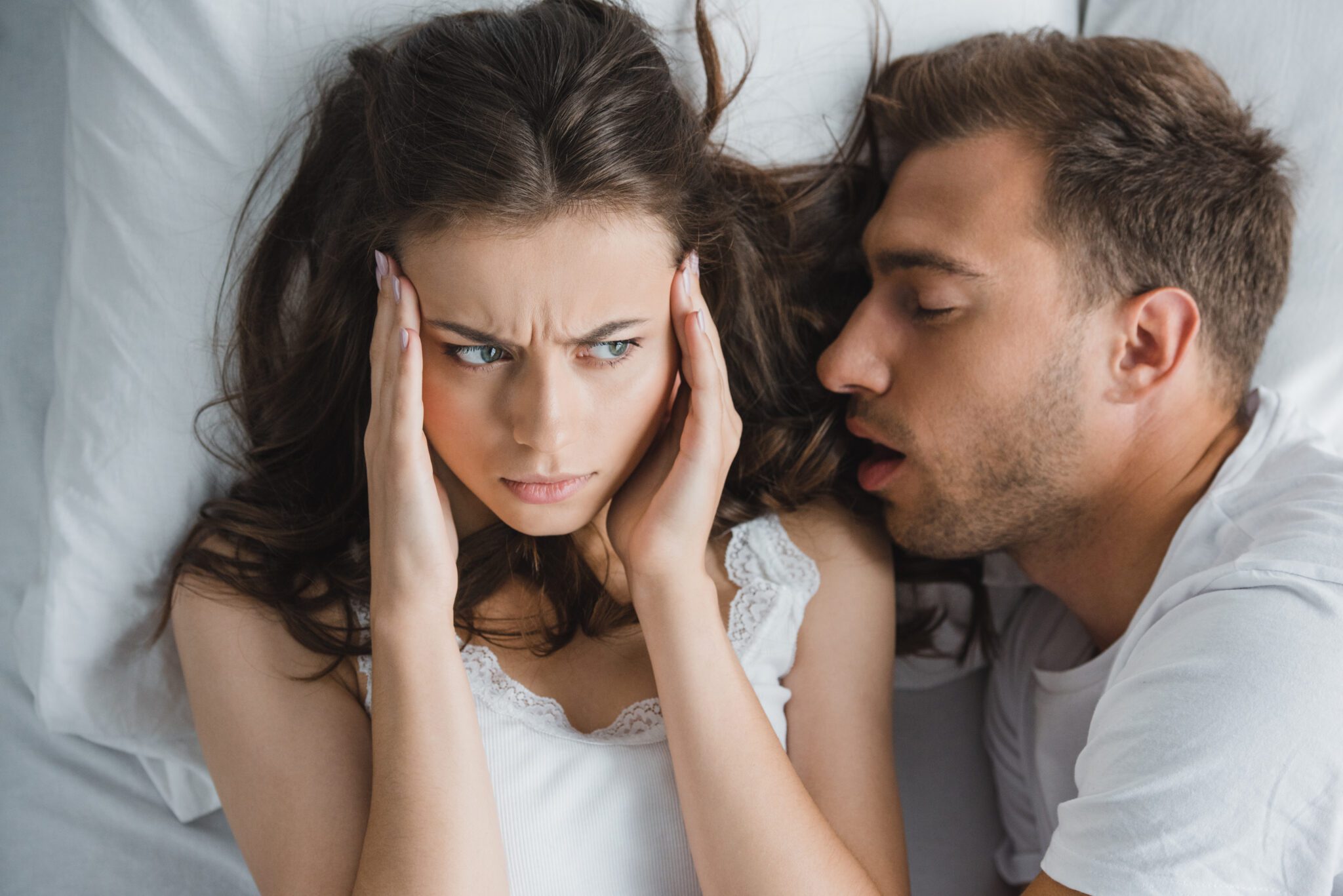 man snoring in his partners ear, disturbing her rest