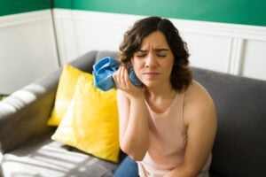 young woman on couch with ice pack on jaw, severe tooth pain