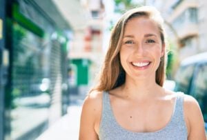 young woman smiling on a city street, perfect white smile