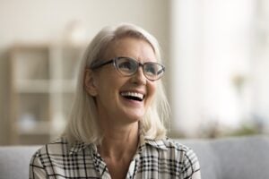 mature woman smiling on a couch, new dental implants