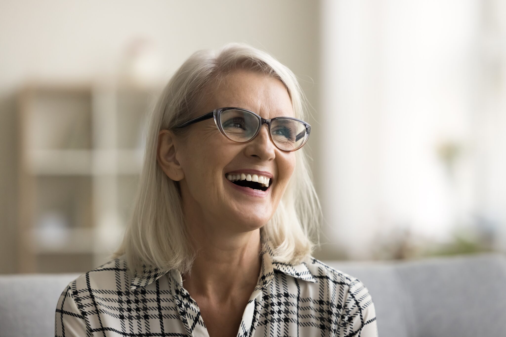 mature woman smiling on a couch, new dental implants