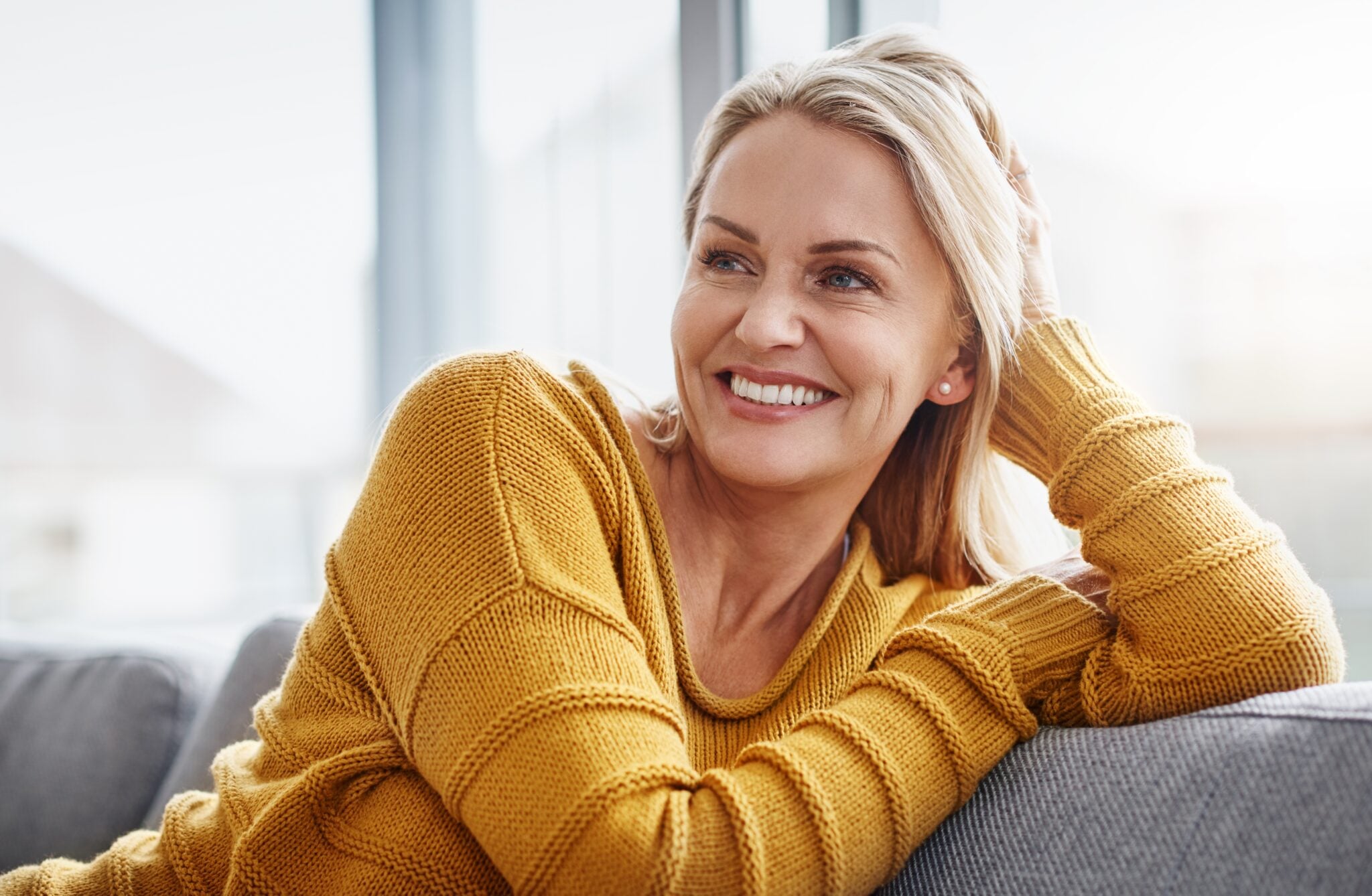 mature woman sitting on a couch, perfect smile