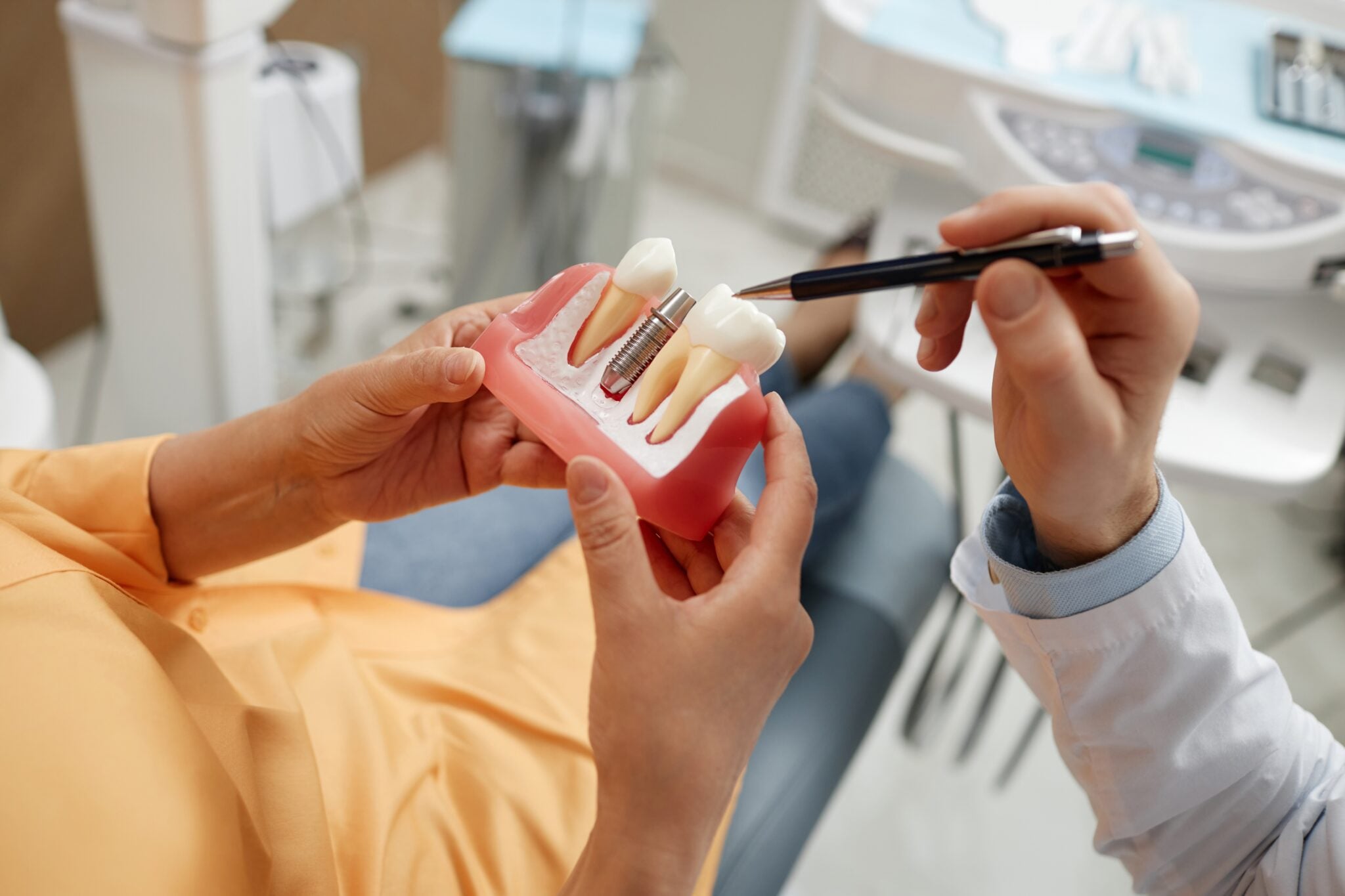 closeup of a dentist showing a patient an implant model